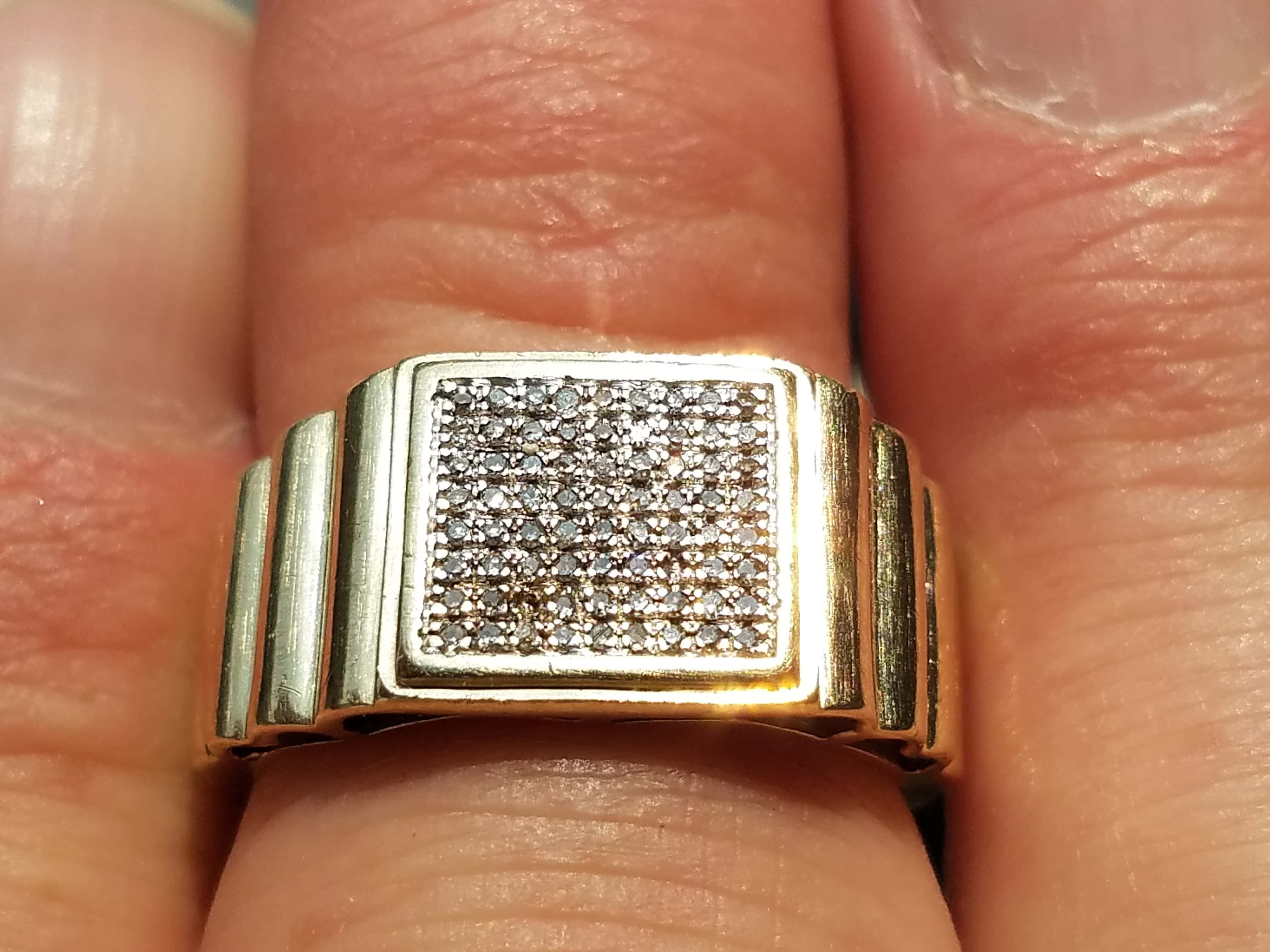 Diamond Ring Set in gold Held in Between Fingers in Front of Denim Jeans Background