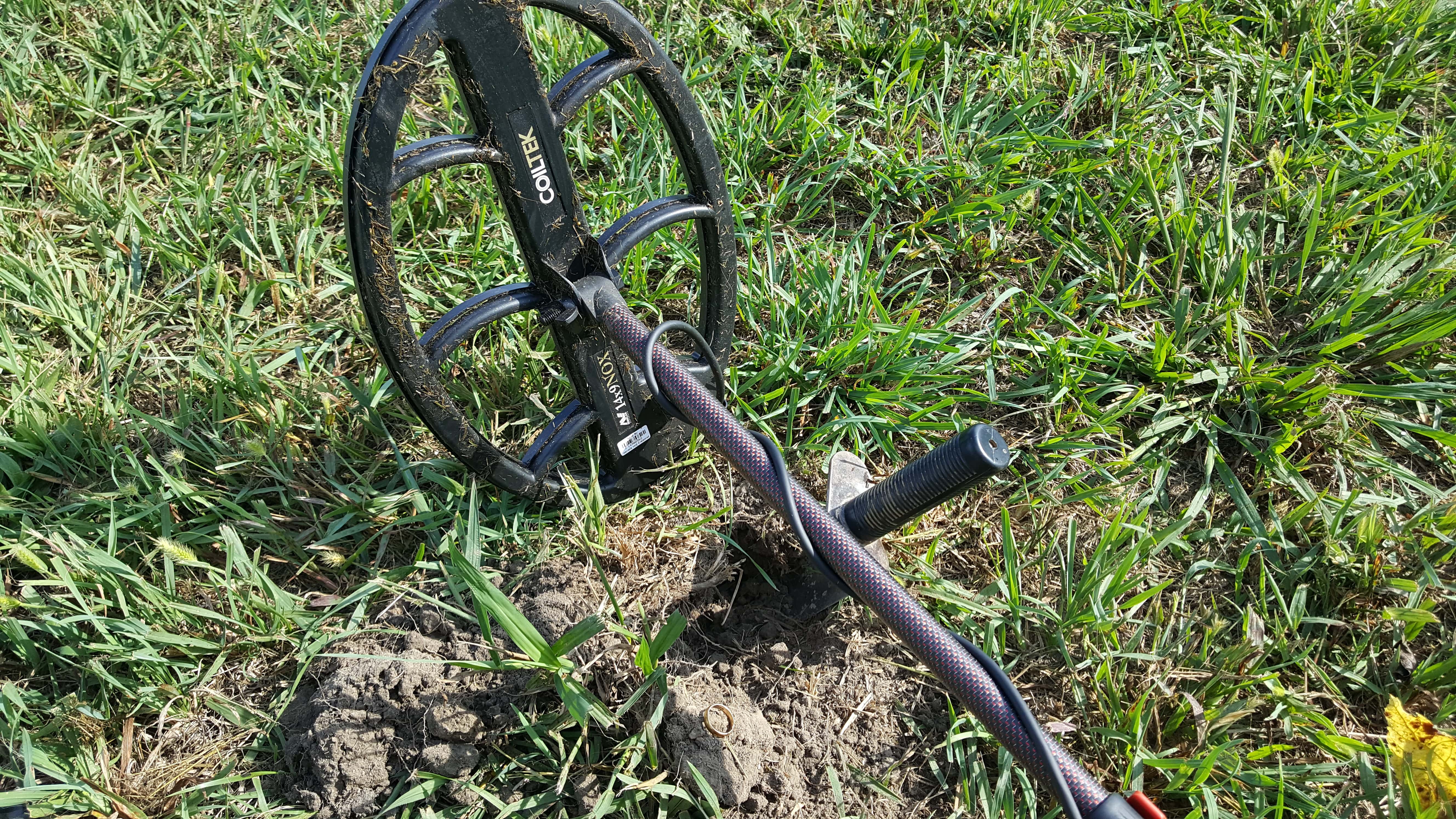 Grassy Coiltek 14 x 9 Search Coil in the Background with Grassy Lawn and Digger Pressed in Dirt